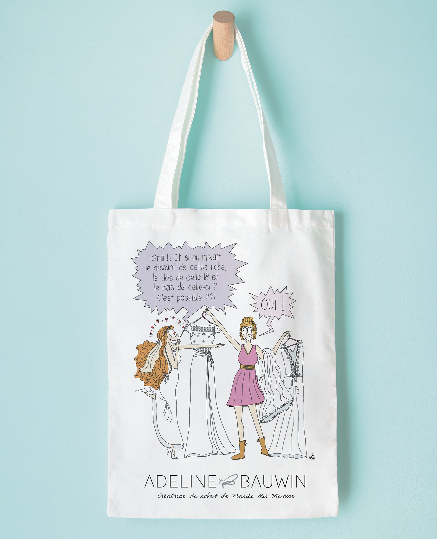 Illustration dessinée représentant deux femmes autour d’une robe de mariée sur mesure, réalisée pour la créatrice Adeline Bauwin, imprimée sur un tote bag blanc