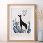 Illustration représentant un cerf stylisé entouré de feuillages et de fleurs, encadrée dans un cadre en bois clair avec marie-louise, présentée dans un décor minimaliste aux tons naturels.